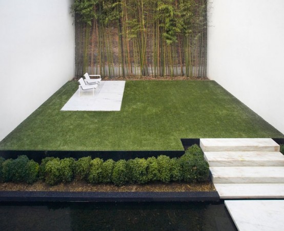 uno spazio giardino minimalista con gradini in pietra, un prato curato, vegetazione piantumata e bambù e mobili minimalisti