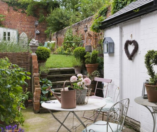 un accogliente rustico incontra lo spazio giardino vintage con mobili da giardino vintage, un prato fresco e vegetazione in vaso