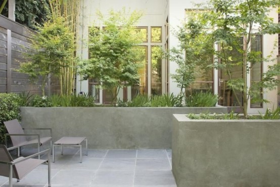 un piccolo giardino in una casa a schiera con piastrelle in pietra, fioriere in cemento, mobili minimalisti e vegetazione e alberi che crescono