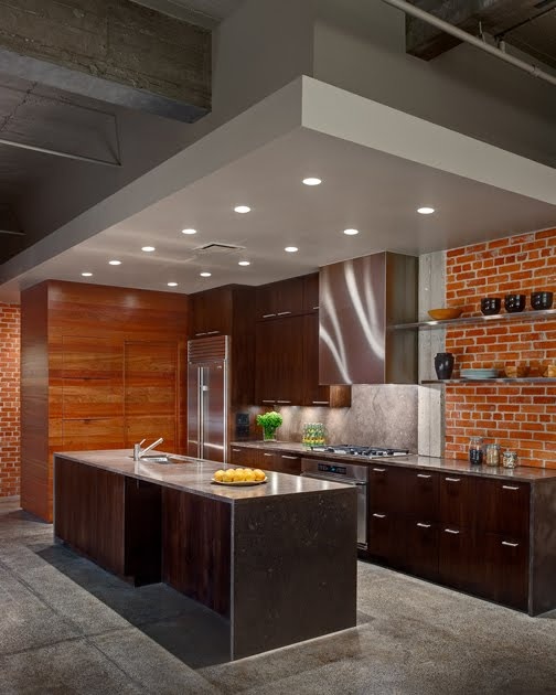una cucina moderna scura con un muro di mattoni rossi e ricchi mobili in legno colorato per un look accattivante e audace