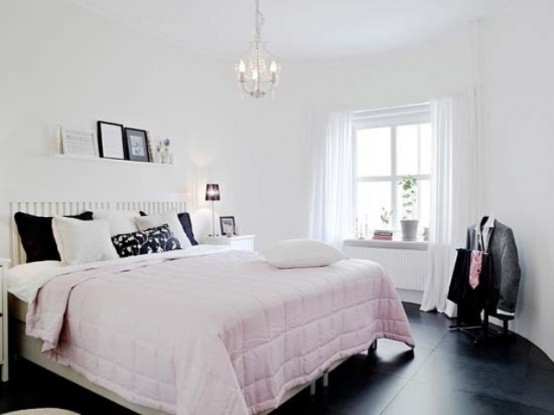 un'accogliente camera da letto in bianco e nero più lievi tocchi rosa, cuscini, un lampadario di cristallo