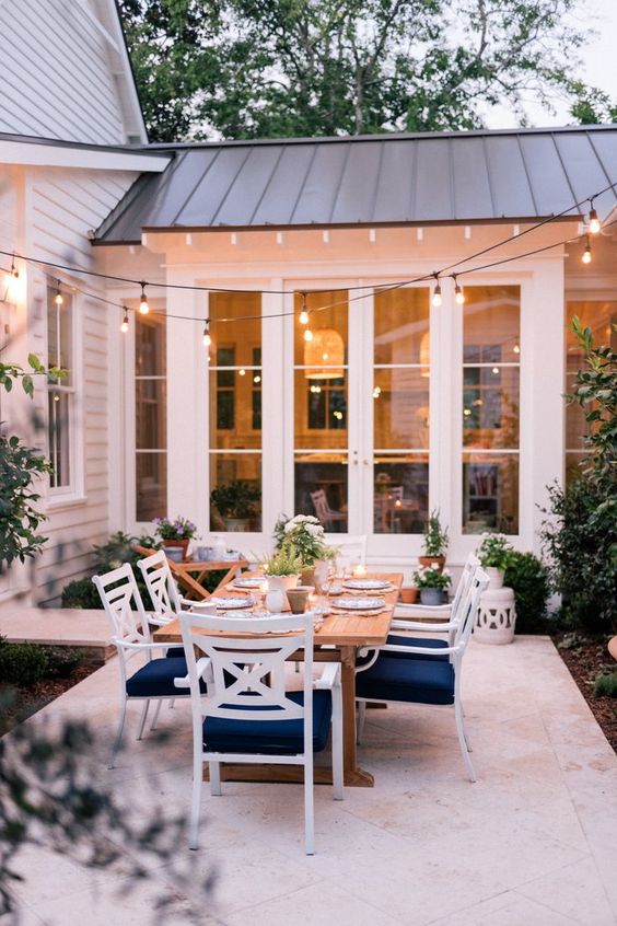 includi uno spazio da pranzo nel tuo patio con un tavolo e sedie bianche e blu scuro, abbelliscilo con piante in vaso