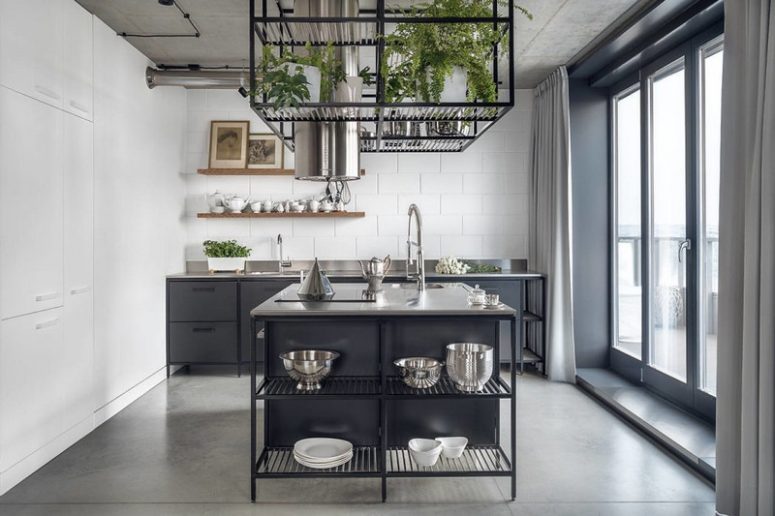 La cucina è realizzata con armadi in metallo nero e un'isola della cucina, con un muro di piastrelle della metropolitana e un cubo con vegetazione in vaso