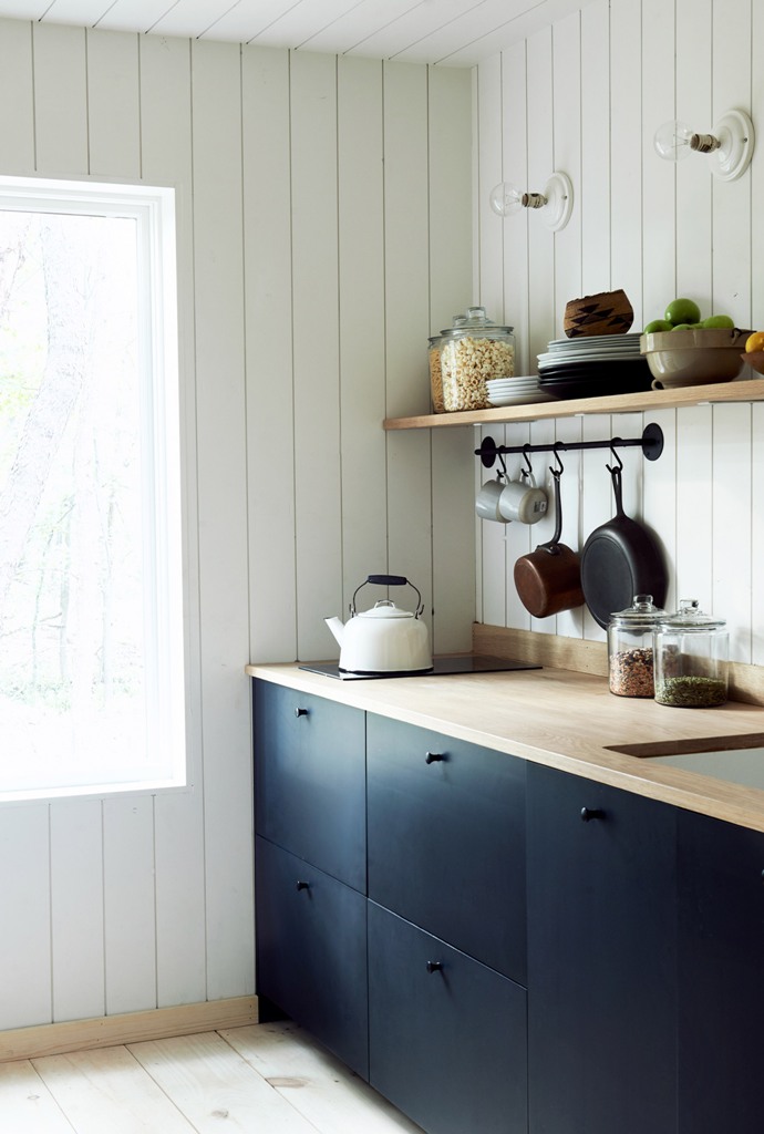La cucina è realizzata con eleganti armadi blu scuro, ripiani e ripiani in legno di colore chiaro e c'è molta luce naturale