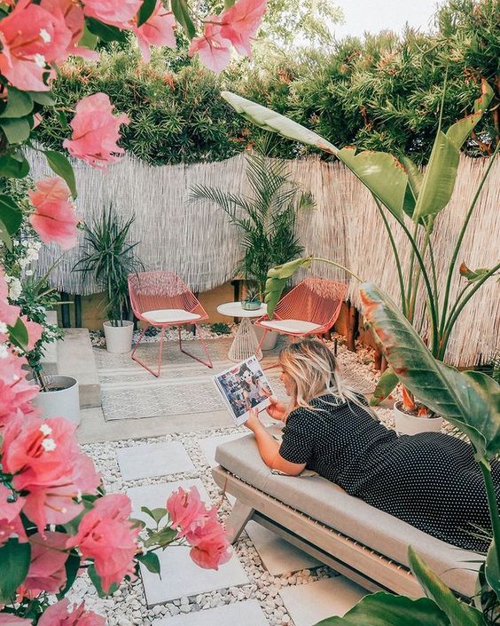 uno splendido patio tropicale con sedie rosa e fiori rosa, un comodo divano letto, piante tropicali in vaso