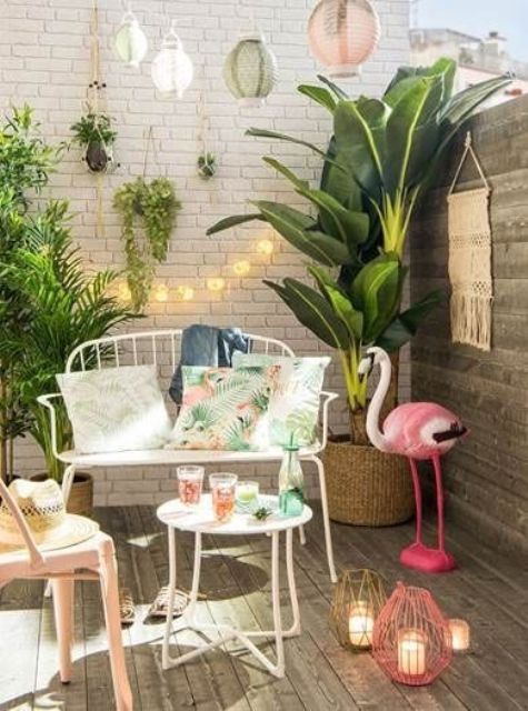 un mini mazzo tropicale con piante in vaso, un fenicottero rosa, lanterne a candela colorate, eleganti mobili e luci forgiati bianchi