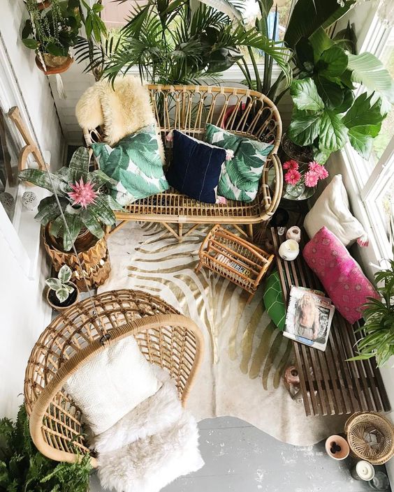 un balcone tropicale con mobili in rattan, piante torpiche in vaso, cuscini colorati e un tappeto zebrato