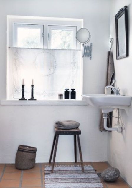 un bagno nordico bianco con un tocco vintage, cadnles, specchi e lampade plus e un cestino per la conservazione