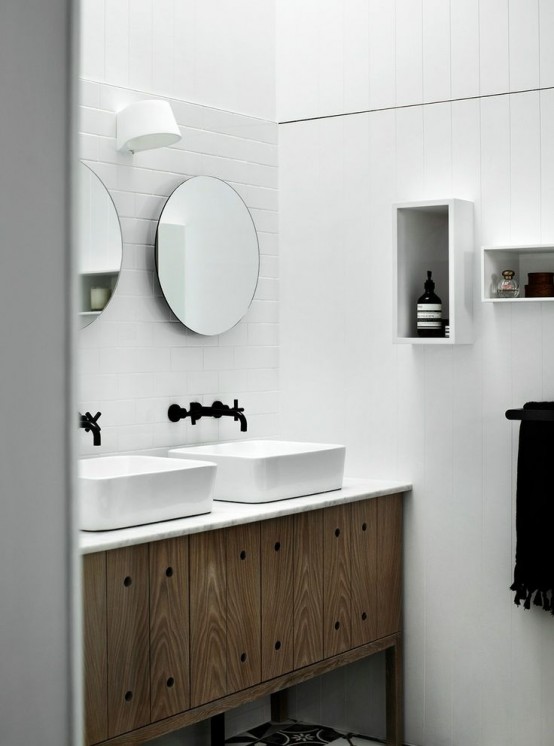 un semplice bagno nordico fatto con piastrelle bianche, un lavabo in legno e mensole a scatola sul muro