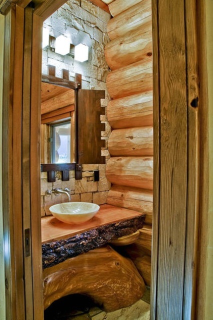 un bagno rivestito in legno di colore chiaro con un muro in pietra naturale