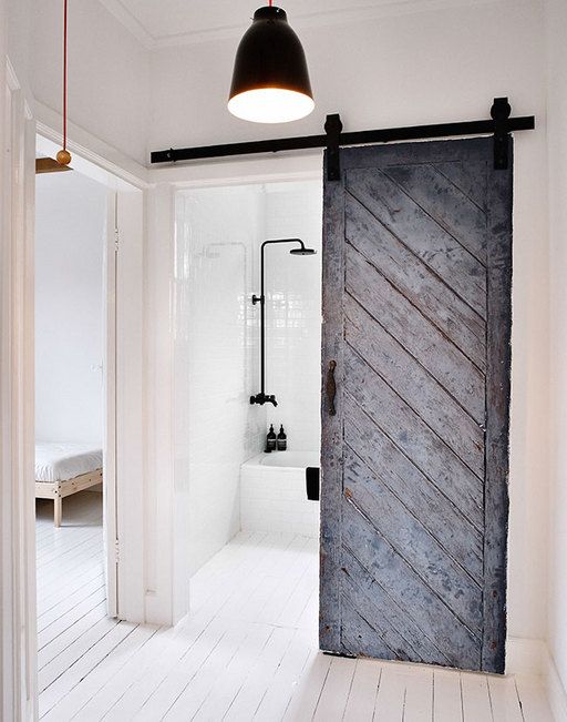 una porta scorrevole rustica in grigio contrasta lo spazio moderno e aggiunge colore