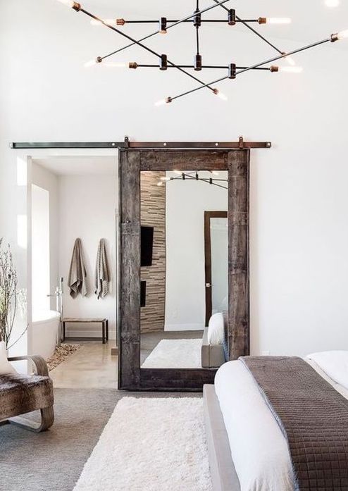 una porta rustica in legno stagionato con un grande specchio conferisce un tocco rustico e un tocco accogliente