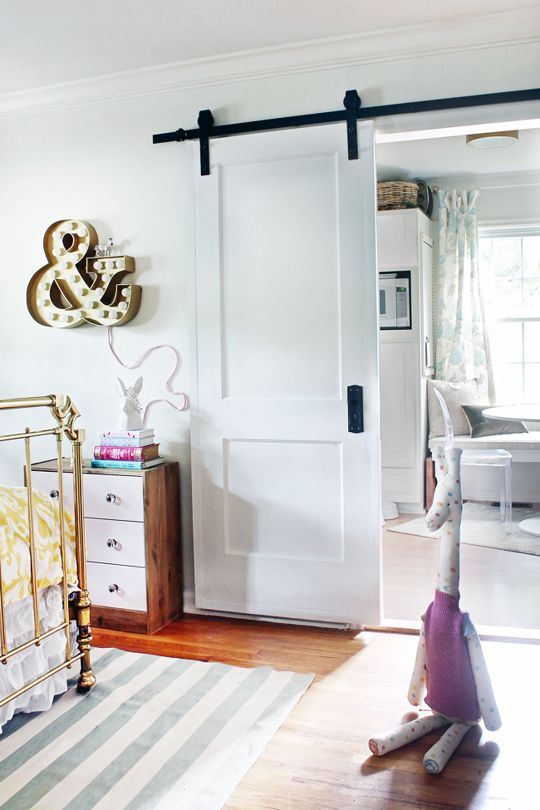 una semplice porta scorrevole bianca consente di risparmiare spazio in un piccolo asilo nido e si abbina molto bene agli interni
