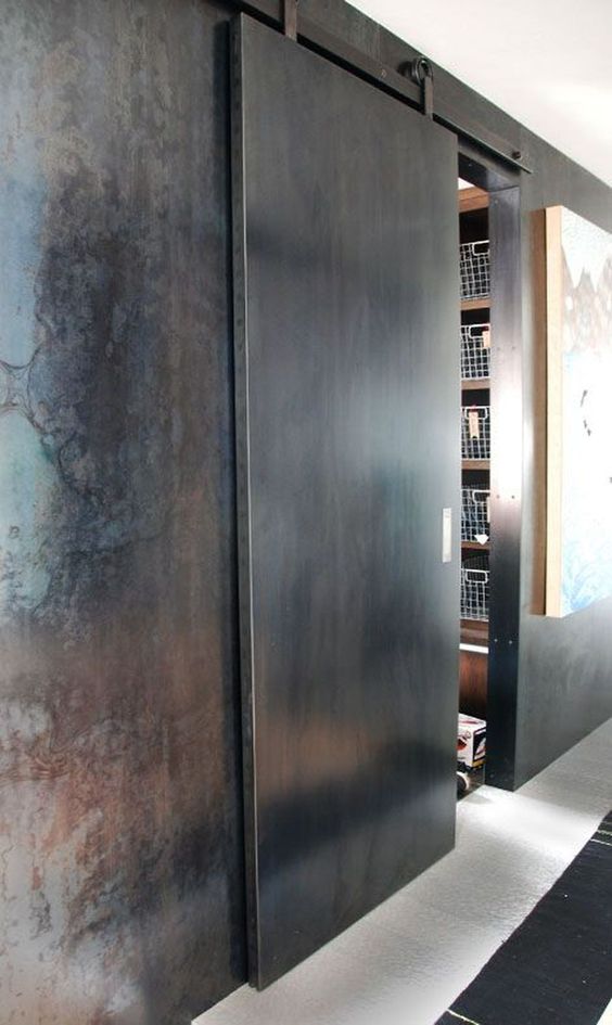 una porta scorrevole in metallo continua il tema della decorazione industriale e ruvida dello spazio