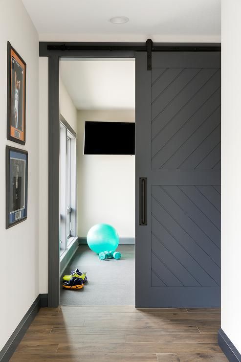 una porta granaio scorrevole grigia nasconde una piccola palestra privata e allo stesso tempo risparmia spazio