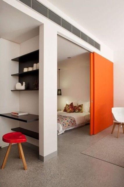 una porta scorrevole arancione brillante aggiunge colore allo spazio e lo salva