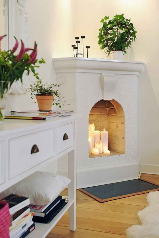 un caminetto bianco semplice e piccolo con candele a colonna è un'idea interessante per uno spazio moderno