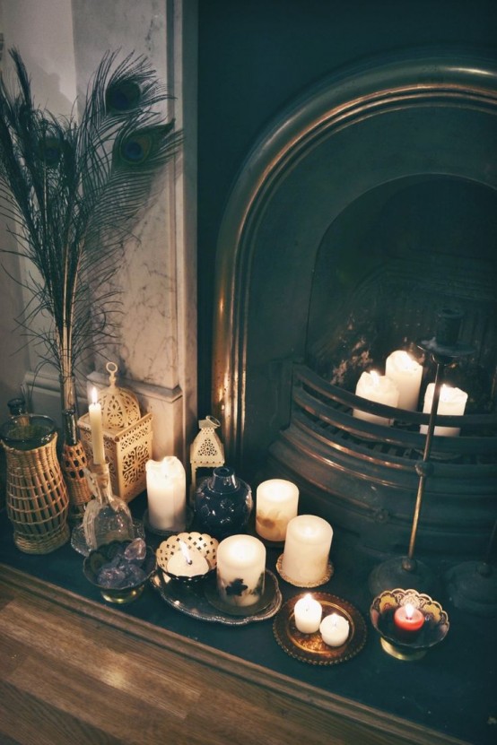 alcune candele nel camino e su piccoli vassoi e piatti accanto ad esso per un'atmosfera boho