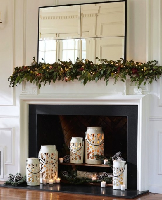 bellissime lanterne bianche a forma di fiocco di neve con candele, pigne e rami di abete per un caminetto pronto per le vacanze