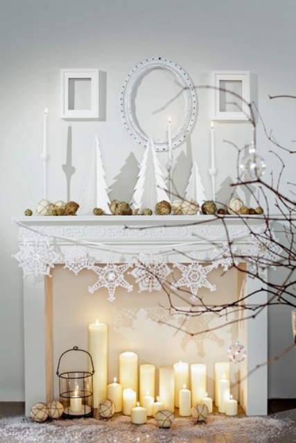 un caminetto invernale chic con candele a colonna, una lanterna a candela e fiocchi di neve per le vacanze
