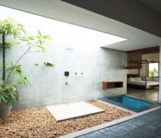 una doccia esterna contemporanea con un muro di cemento, ciottoli e vegetazione