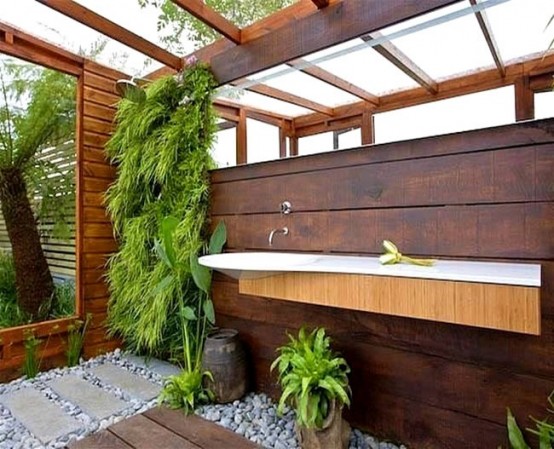 uno spazio doccia esterno contemporaneo con una parete livign, ciottoli e un lavabo galleggiante