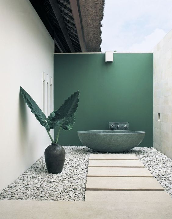 un raffinato bagno esterno minimalista con parete e vasca da bagno verdi, ciottoli, piastrelle in pietra e un grande vaso