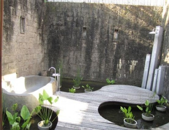 un bagno esterno moderno e stimolante con un pavimento in legno, una vasca in pietra e piante in vaso