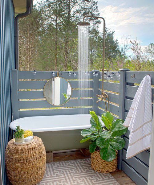 un accogliente bagno in stile rustico nascosto da schermi, una vasca da bagno in verde e alcuni pouf e fioriere in vimini
