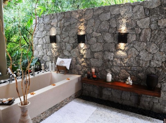 uno spazio naturale con un muro di pietra, una grande vasca da bagno, una mensola e elementi incorporati