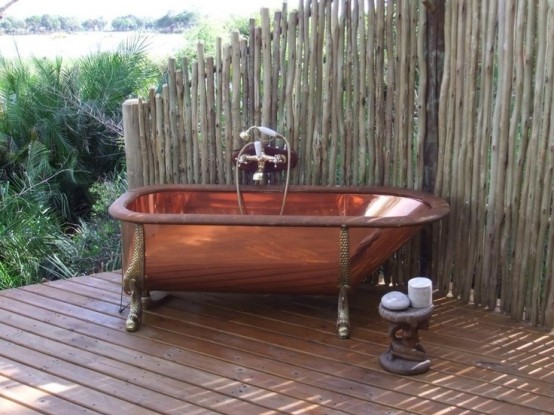 un angolo del bagno all'aperto di ispirazione vintage con una vasca in rame e un tavolino battuto