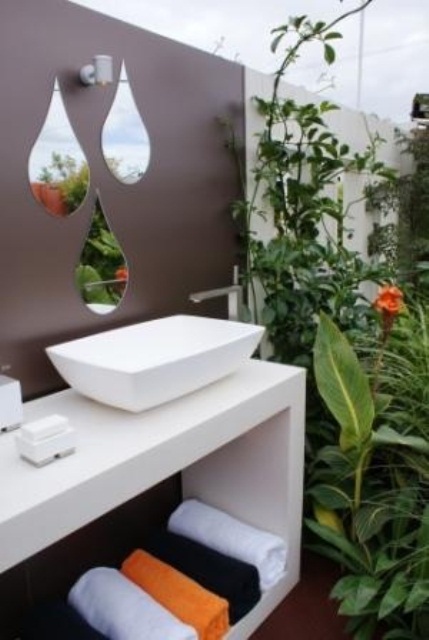 un piccolo angolo del bagno moderno con una vanità galleggiante, un lavandino e specchi a forma di goccia