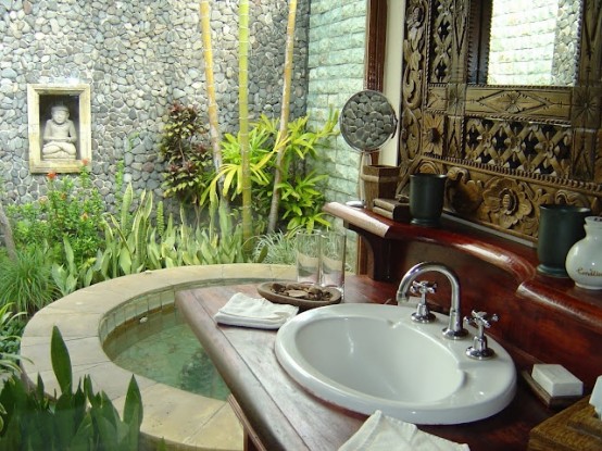 un'oasi asiatica del bagno all'aperto con una grande vasca-piscina, un lavandino, uno specchio intarsiato e molto verde
