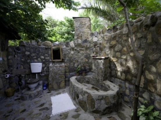 un bagno esterno rustico completamente in pietra e una vasca da bagno in pietra