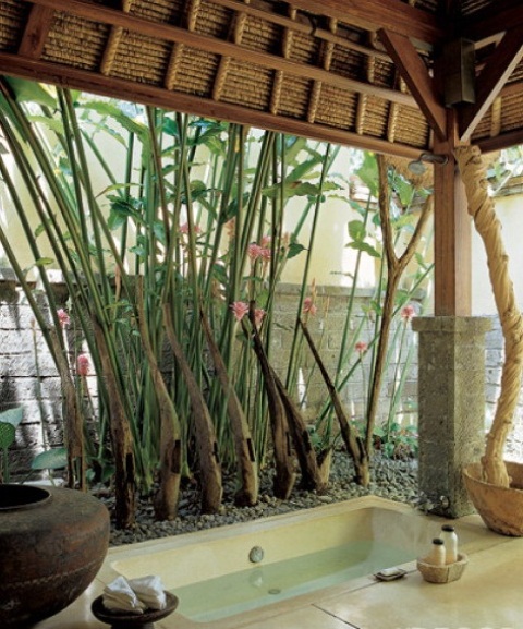 un bagno esterno in stile zen con una vasca incorporata, ciottoli, vasi e alberi viventi e vegetazione