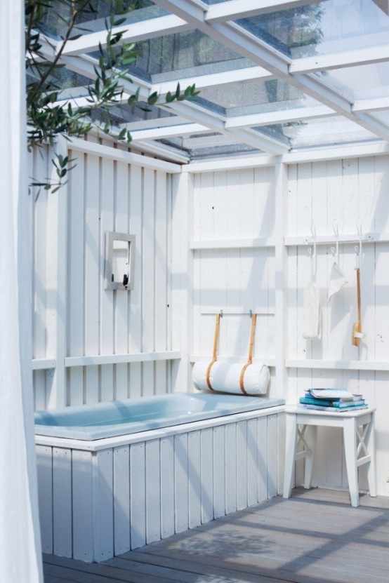 un bagno esterno ispirato al mare fatto con beadboard, una vasca blu e alcuni accessori più asciugamani blu