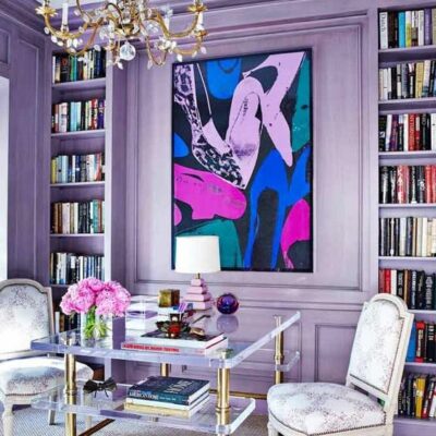 un audace soggiorno glam con pareti lilla e scaffali incorporati e un'opera d'arte luminosa è pieno di colori teneri