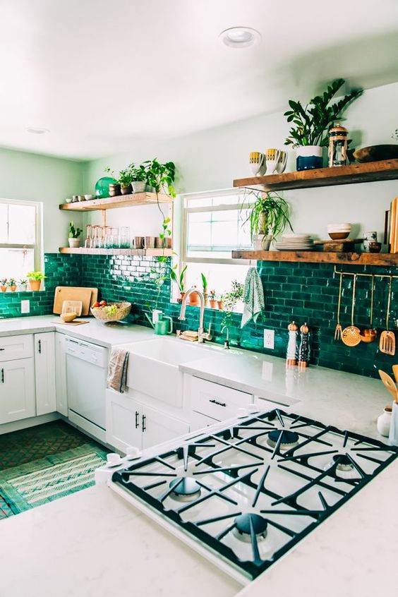 una cucina boho con mobili bianchi, un backsplash di piastrelle verde brillante, molta vegetazione e tappeti verdi
