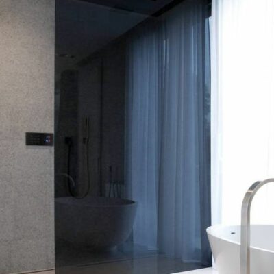 un bagno minimalista con una doccia in vetro fumé per separare lo spazio delicatamente e con una sensazione spigolosa