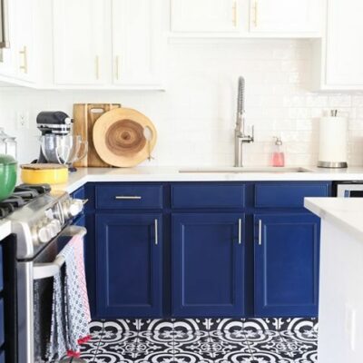 una cucina chic e audace con armadi blu scuro e controsoffitti bianchi e piastrelle a mosaico blu scuro e bianche sul pavimento
