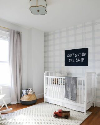 un asilo nido accogliente e luminoso con un muro a quadri con sfumature chiare e un divertente tappeto a pois bianco