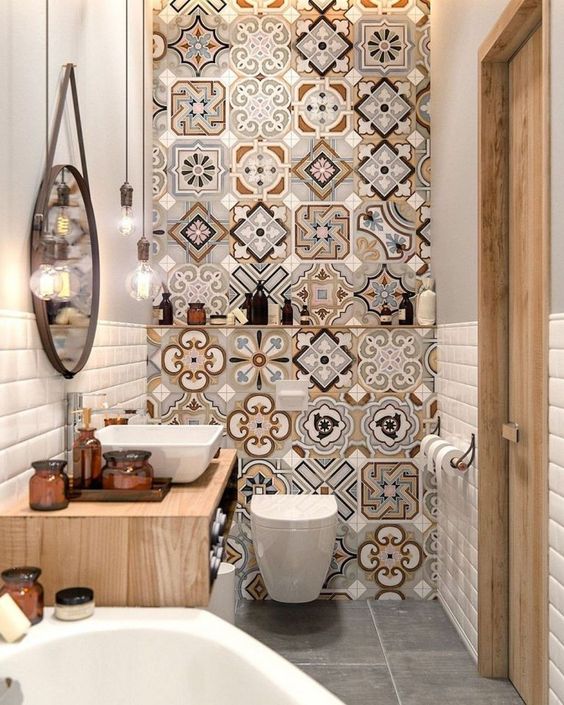 un bagno luminoso e piccolo con un muro di piastrelle a mosaico, un lavabo in legno galleggiante, una vasca, uno specchio rotondo e lampadine