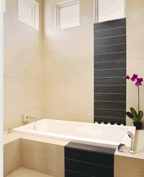 un bagno beige decorato con piastrelle scure e una vasca da bagno bianca è uno spazio chic