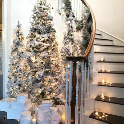 un ingresso da favola invernale chic con alberi di Natale affollati, luci e ornamenti neutri più candele in giro