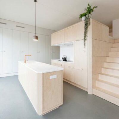 L'isola della cucina si abbina al mobile contenitore e alla zona letto a soppalco creando uno spazio coeso con un tocco moderno