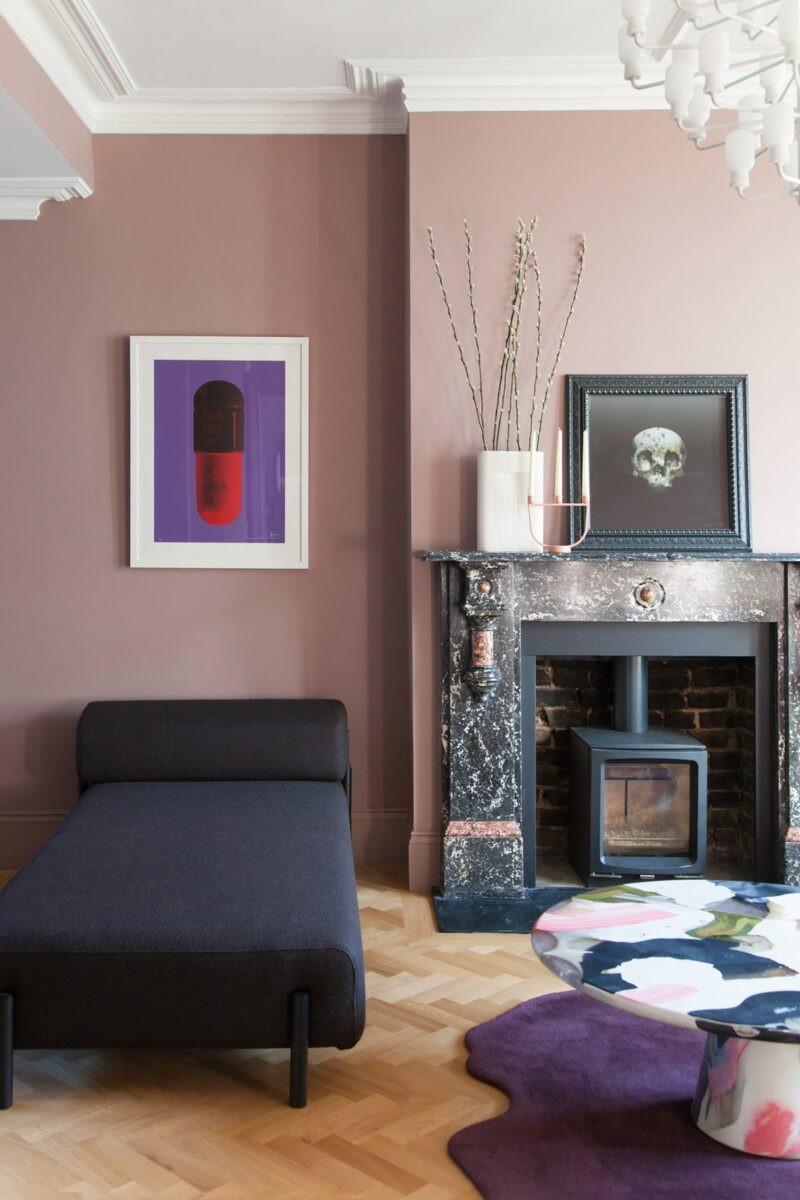 Il soggiorno presenta pareti color malva, un mini focolare nel camino non funzionante e opere d'arte accattivanti